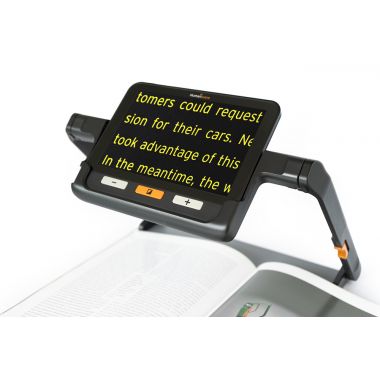 explorē 8 digital magnifier on its reading stand placed on an open book. The device's screen displays enlarged text, making reading easier for people with vision loss.