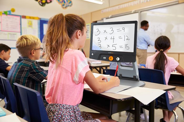 Schoolgirl in class using Reveal 16 to enlarge a mathematical problem presented on the whiteboard at the front of the classroom.